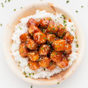 An overhead shot of a dish with white rice and general Tso's tofu on top