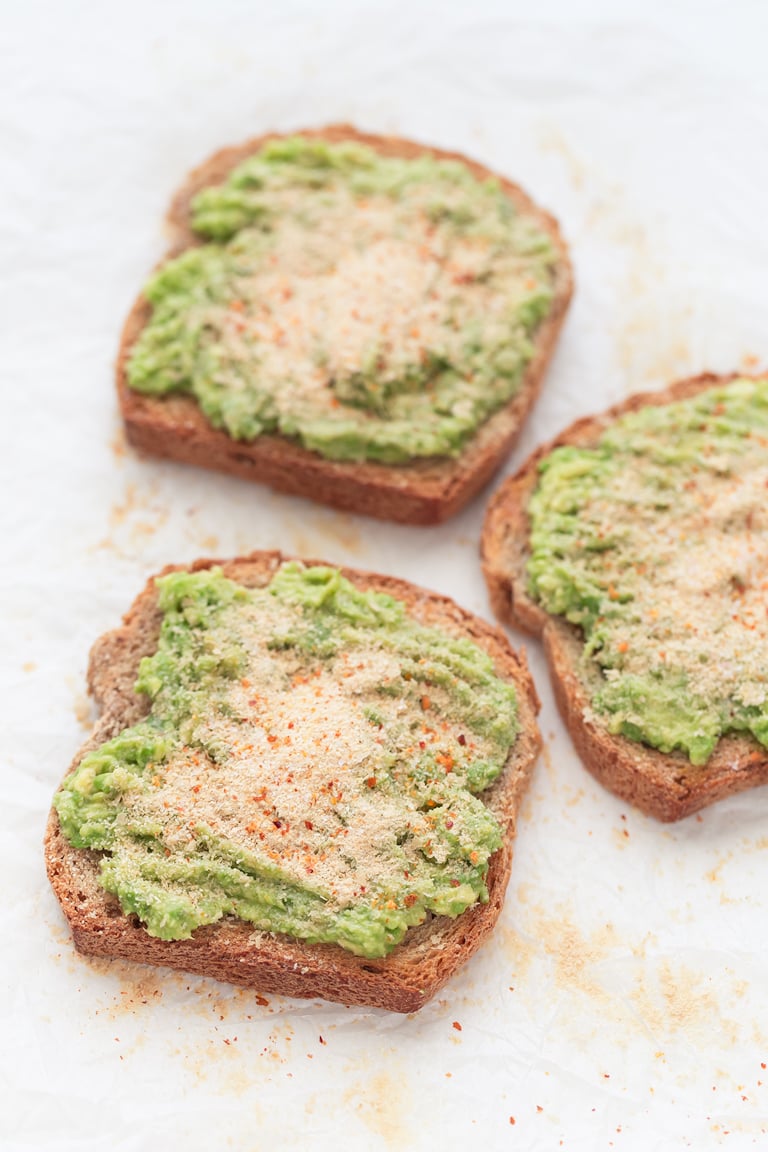 Photo of 3 slices of avocado toast with some nutritional yeast on top