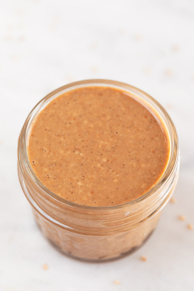 A small glass container with homemade tahini made from toasted sesame seeds