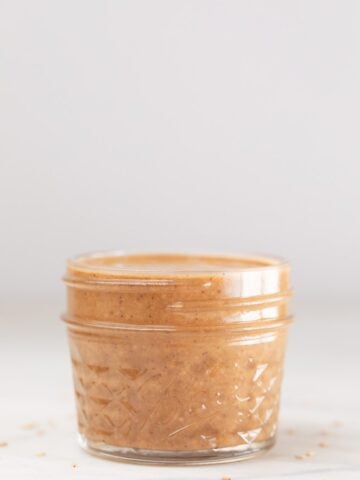A side shot of a small glass container with homemade tahini