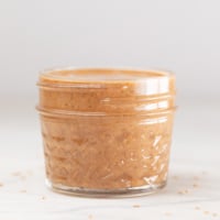 A side shot of a small glass container with homemade tahini