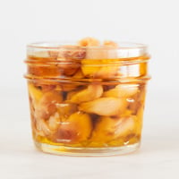 A small picture of a glass container with roasted garlic and covered with oil