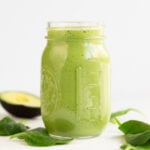A square picture of a glass container with avocado smoothie