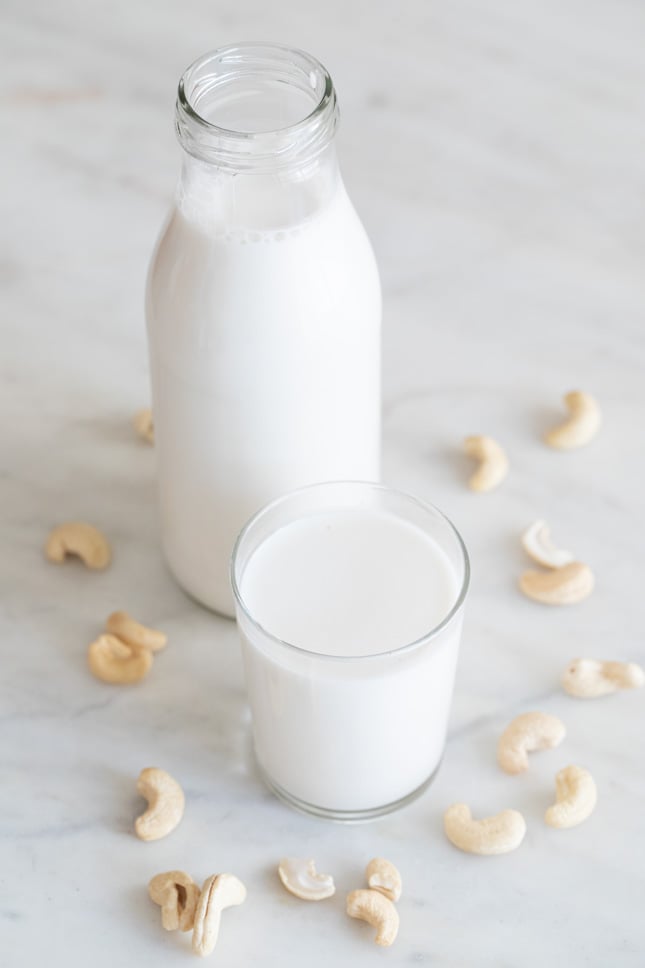 A picture of a glass and a bottle with cashew milk made from scratch