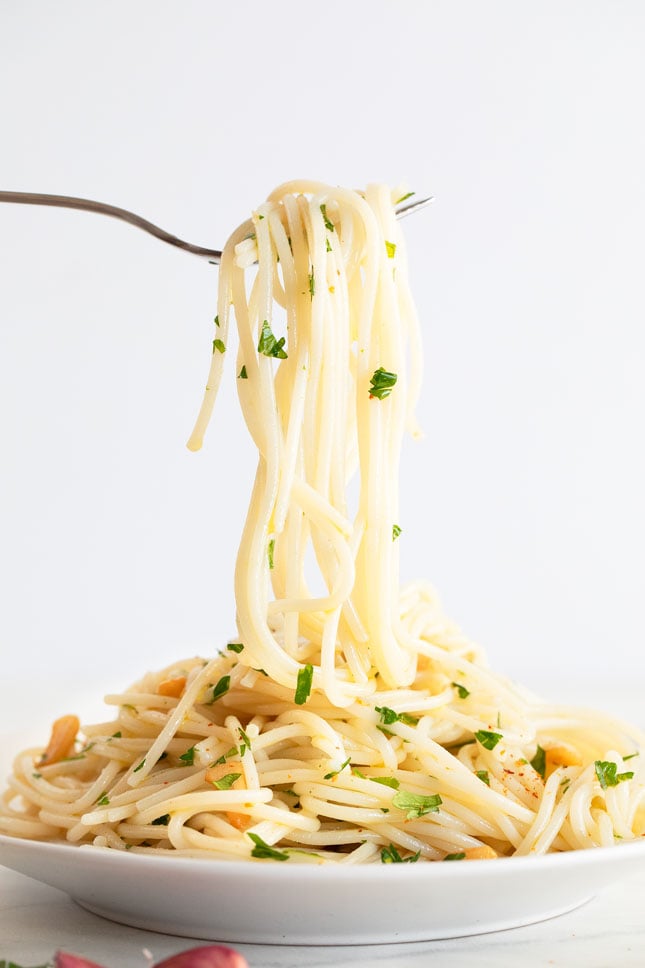 Photo of a fork taking some pasta aglio e olio from a plate