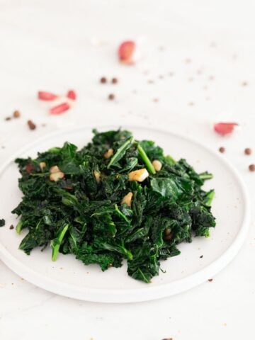 Photo of a plate of sauteed kale decorated with some garlic cloves