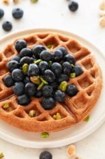 A picture of a with with homemade vegan waffles topped with blueberries and pistachios