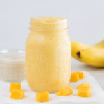 A small picture of a glass jar with mango smoothie
