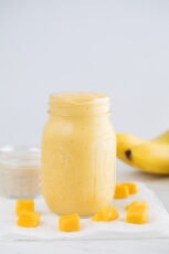 A side shot of a glass jar with mango smoothie
