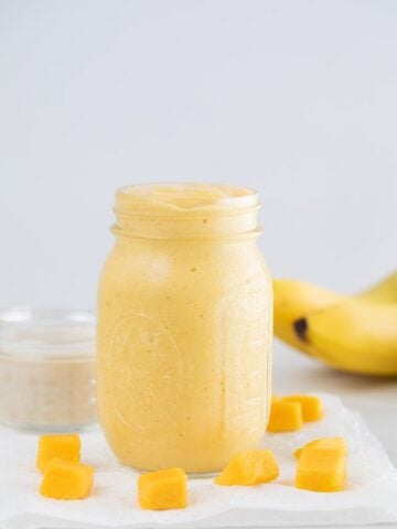 A side shot of a glass jar with mango smoothie