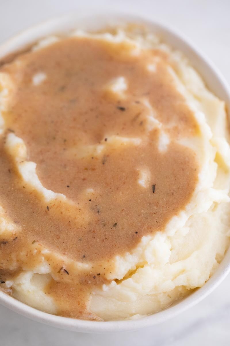 An overhead shot of a bowl with mashed potatoes and some vegan gravy on top