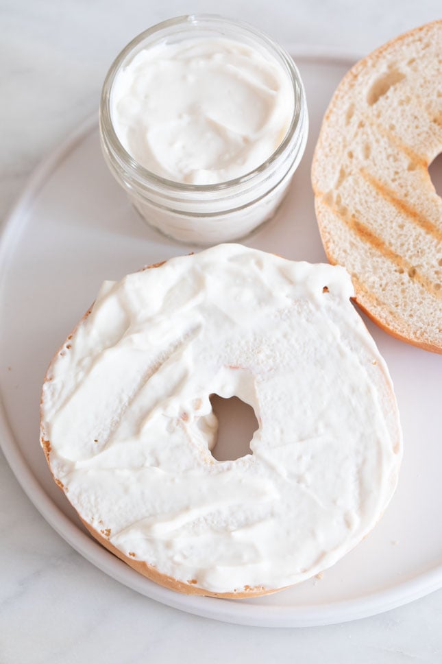 An overhead shot of a sliced and toasted bagel spread with homemade vegan cream cheese