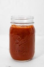 Side shot of a glass jar of red enchilada sauce