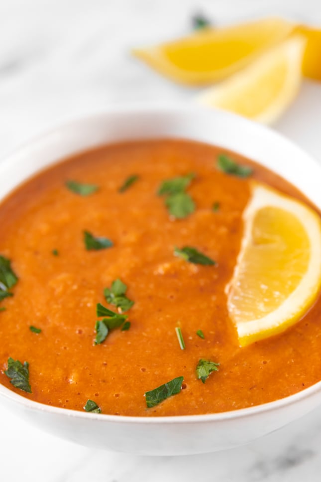 Photo of a bowl of red lentil soup decorated with a sliced lemon