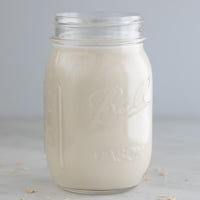 A square picture of a glass jar with homemade oat milk