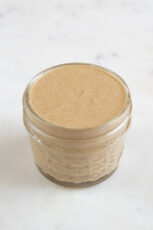 A picture of a small glass container with tahini dressing