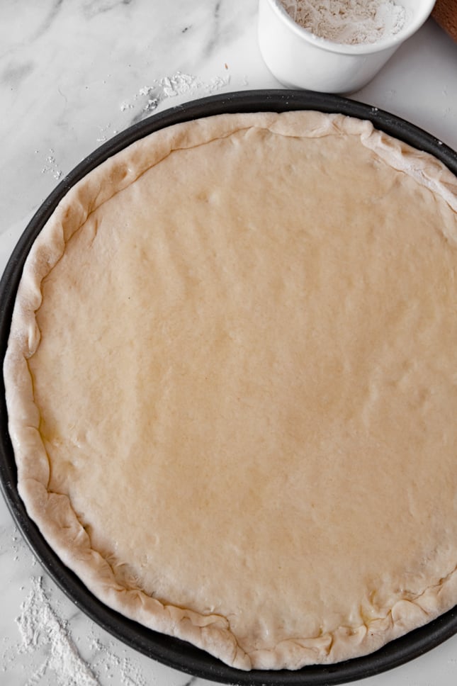 Photo of a homemade pizza dough on a baking dish