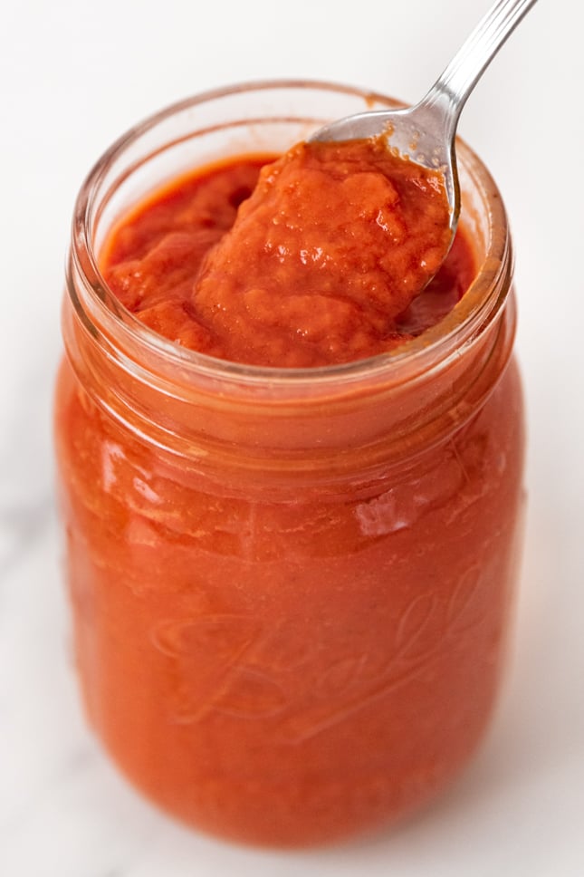 Close-up shot of a jar and a spoonful of pizza sauce