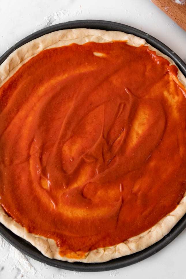Photo of some pizza sauce spread onto a pizza