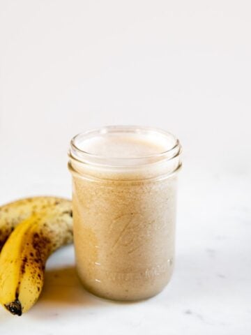 A picture of a jar with banana milk and a couple of bananas