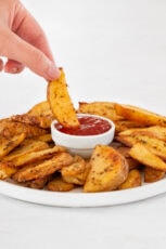 Photo of a potato wedge being dipped in homemade ketchup