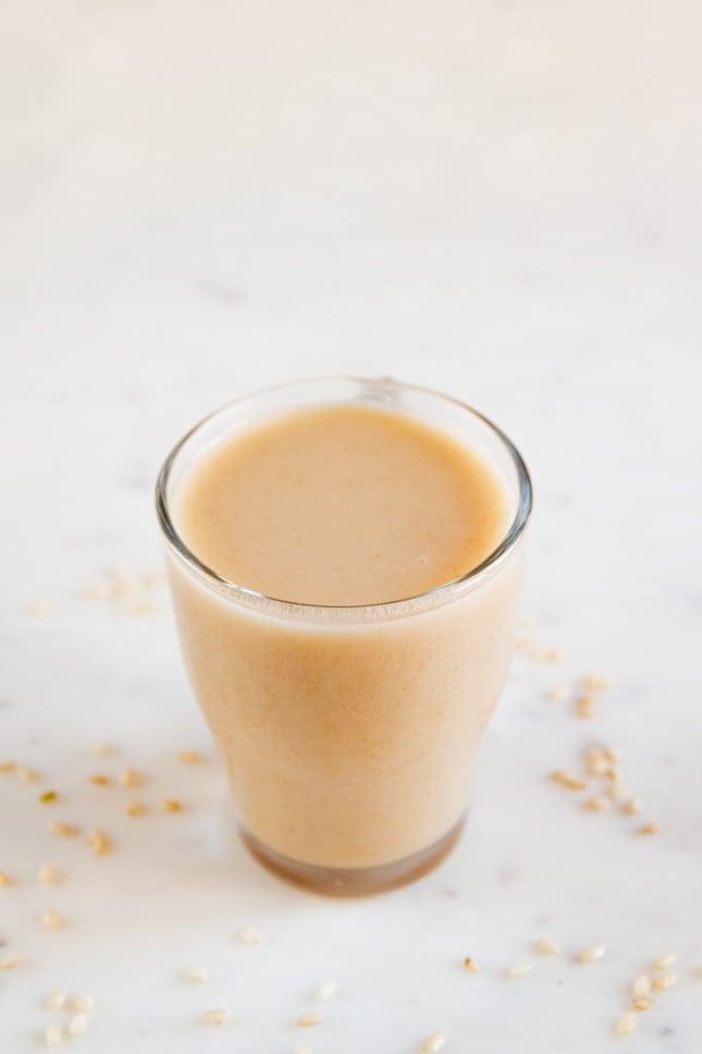 A picture of a glass with homemade rice milk and some brown rice around