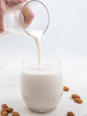 Photo of a jar pouring homemade almond milk into a glass