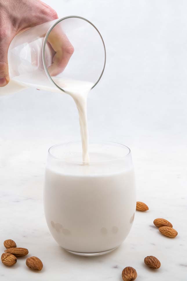 Photo of a jar pouring almond milk into a glass