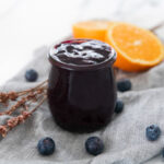 Square photo of a glass jar of blueberry compote