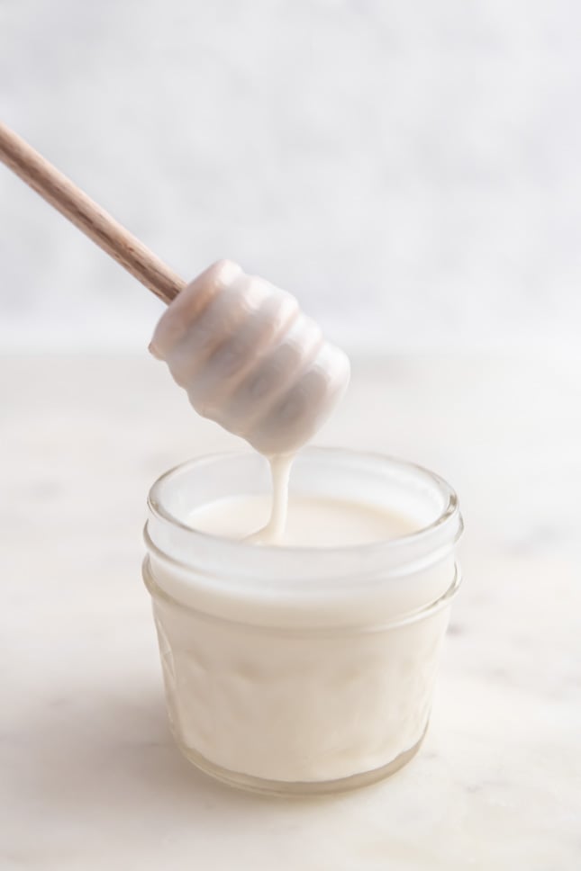 Photo of a glass of coconut butter with a honey dipper