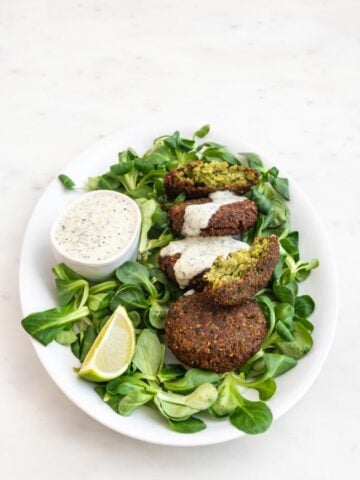 Photo of a plate of falafel and vegan yogurt sauce over some greens