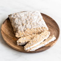 Square photo of a block of tempeh on a wooden plate
