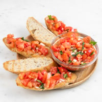 Square photo of a wooden plate of bruschetta