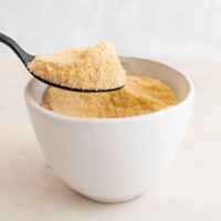 Square photo of a bowl and a spoonful of homemade coconut flour