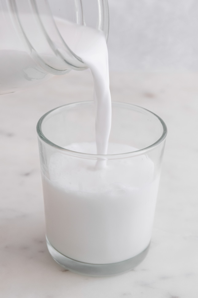 Photo of a bottle of coconut milk pouring the milk into a glass