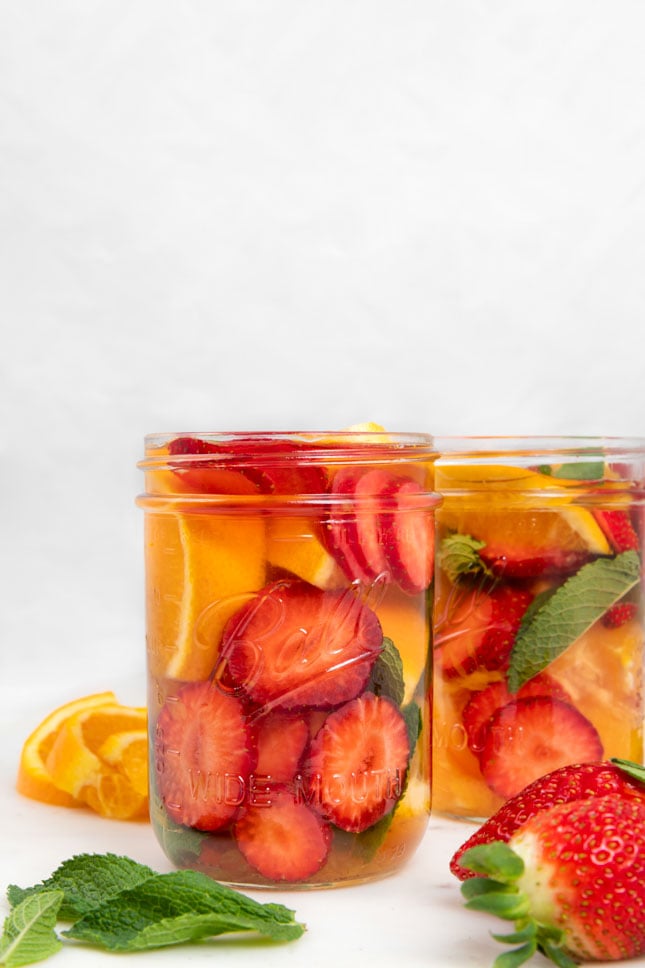 Side shot of 2 glass jars of fruit infused water