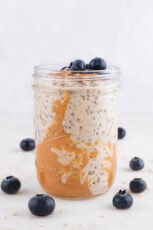 Side shot of a glass jar of overnight oats decorated with some blueberries