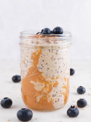 Side shot of a glass jar of overnight oats decorated with some blueberries