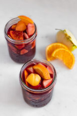 Photo of 2 glass jars of sangria decorated with some sliced fruits