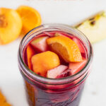 Photo of a jar of sangria decorated with some fruits and the words how to make sangria