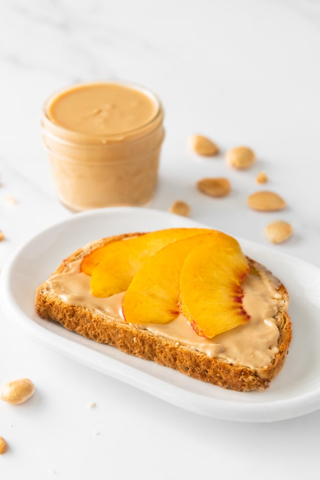Photo of a slice of bread with some almond butter and sliced fruit on top