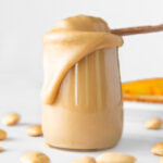 Square photo of a glass jar of creamy almond butter