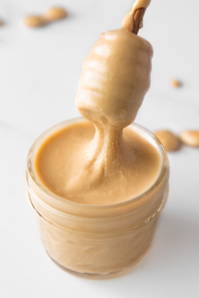 Photo of a glass of almond butter with a honey spoon in it