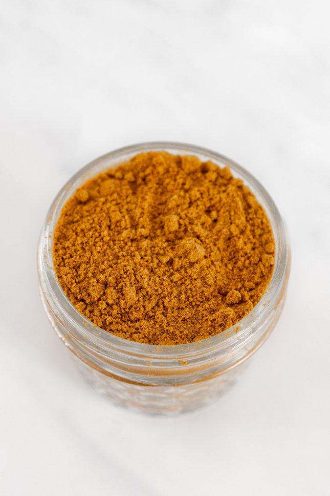 Photo of a small glass jar of curry powder taken from above