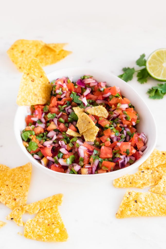 Photo of a bowl of pico de gallo with some tortilla chips