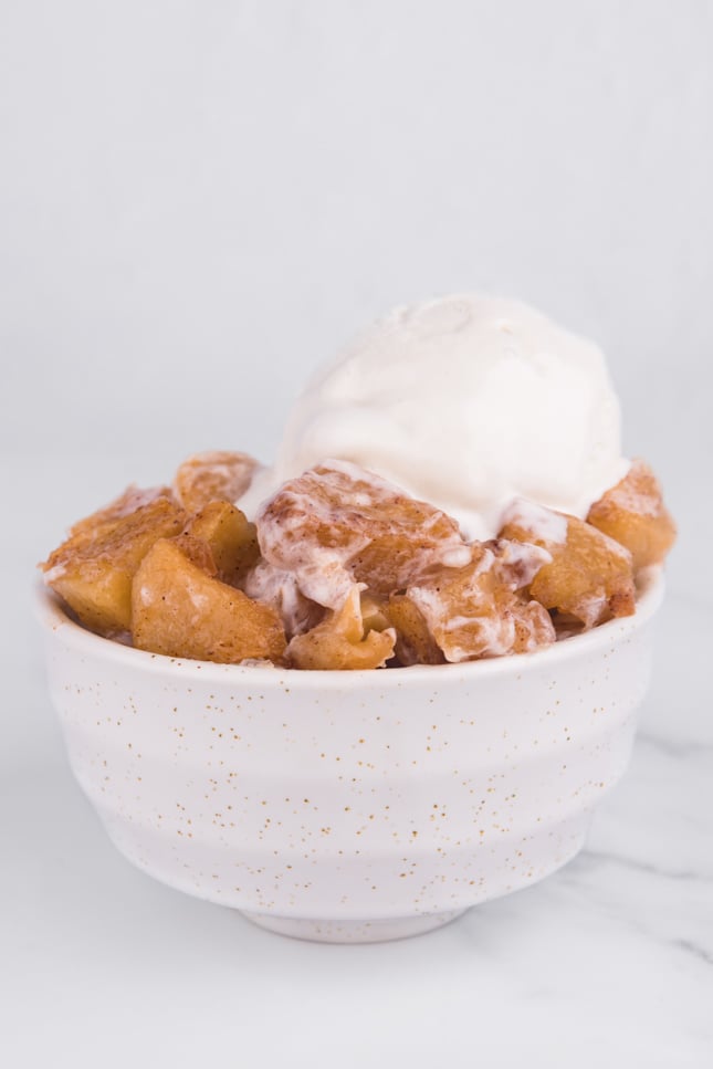 Photo of a bowl of baked apples with vegan vanilla ice cream on top