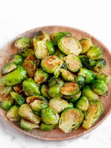 Photo of a wooden plate of sauteed Brussels sprouts