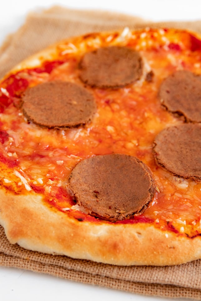 Photo of some slices of vegan pepperoni on a vegan pizza