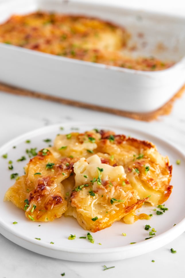 Photo of a plate and a casserole of vegan scalloped potatoes