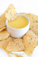 Photo of a bowl of vegan nacho cheese sorrounded with nachos